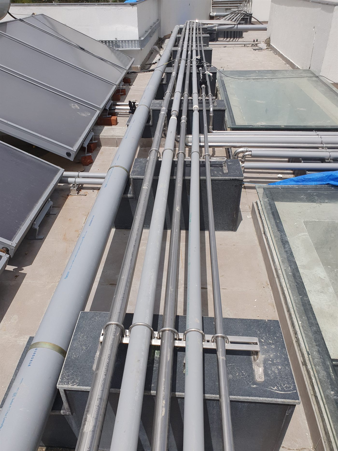 Stainless steel and PEX mains on a common supported run across the terrace
